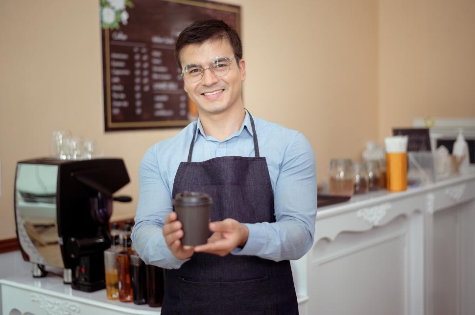 Free Image of Barista behind the counter at a coffee shop, offering complete coffee order 