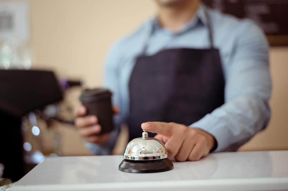 Free Image of Baristas with one finger on the Ring for Service bell at the front counter 