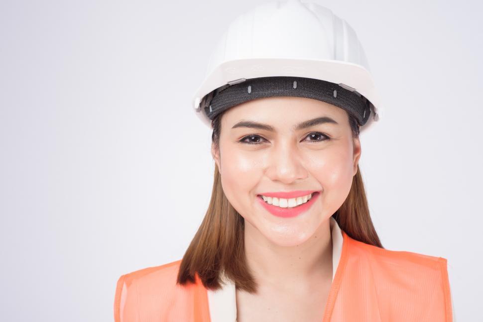 Free Image of a woman wearing a protective hard hat and safety vest facing the camera 