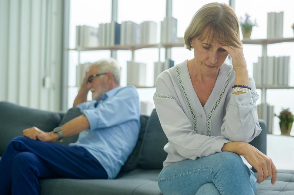 Free Image of Woman is stressed out, with head in hand, man in background is also depressed 