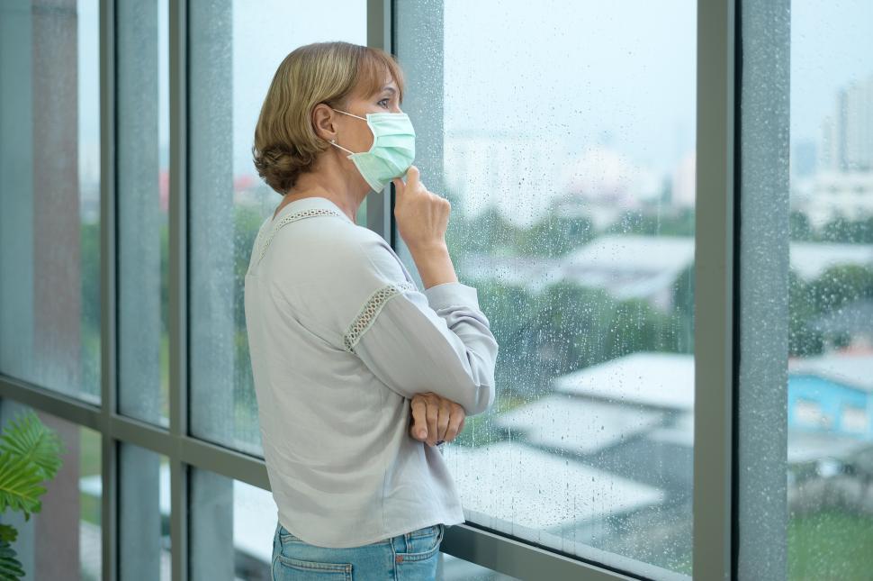 Free Image of Caucasian senior woman wearing a mask, looking out the window 