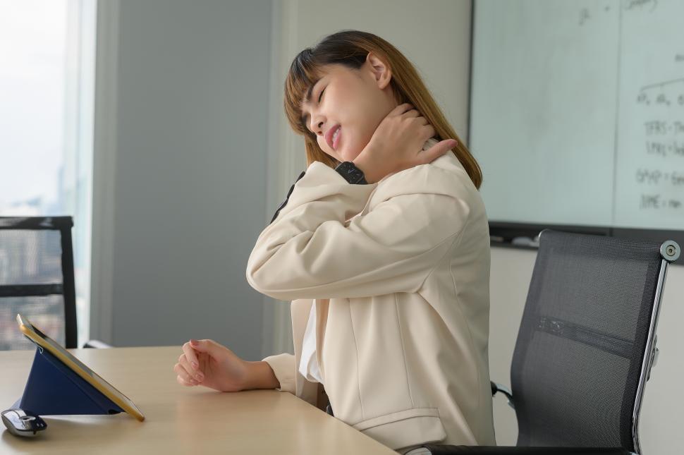 Free Image of Young business woman feeling pain in neck and back in modern office 