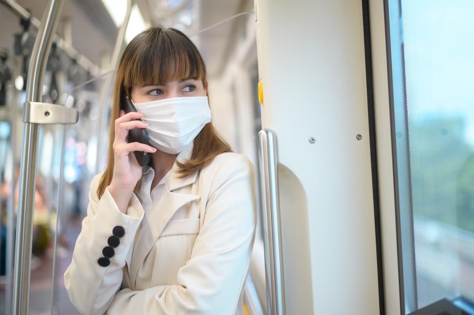 Free Image of Young woman on the phone, wearing protective mask in metro 