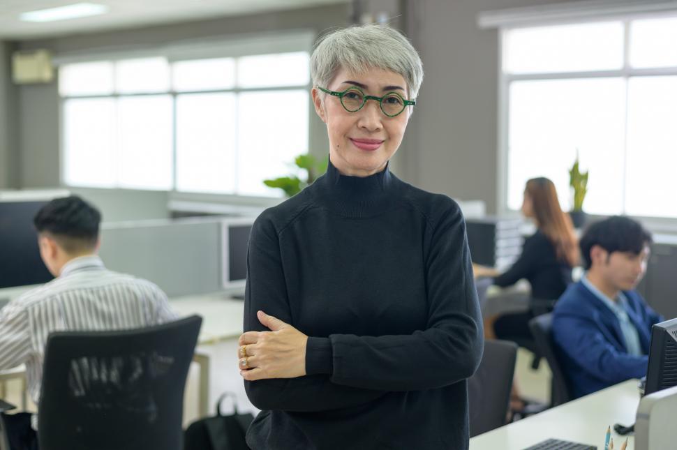Free Image of Portrait of Asian business woman smiling in a busy office 