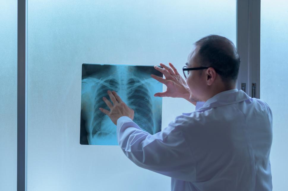 Free Image of The doctor is examining X-ray film, showing to patient 