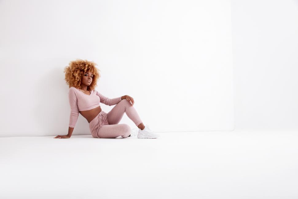 Free Image of black woman with blonde hair sits in white studio 