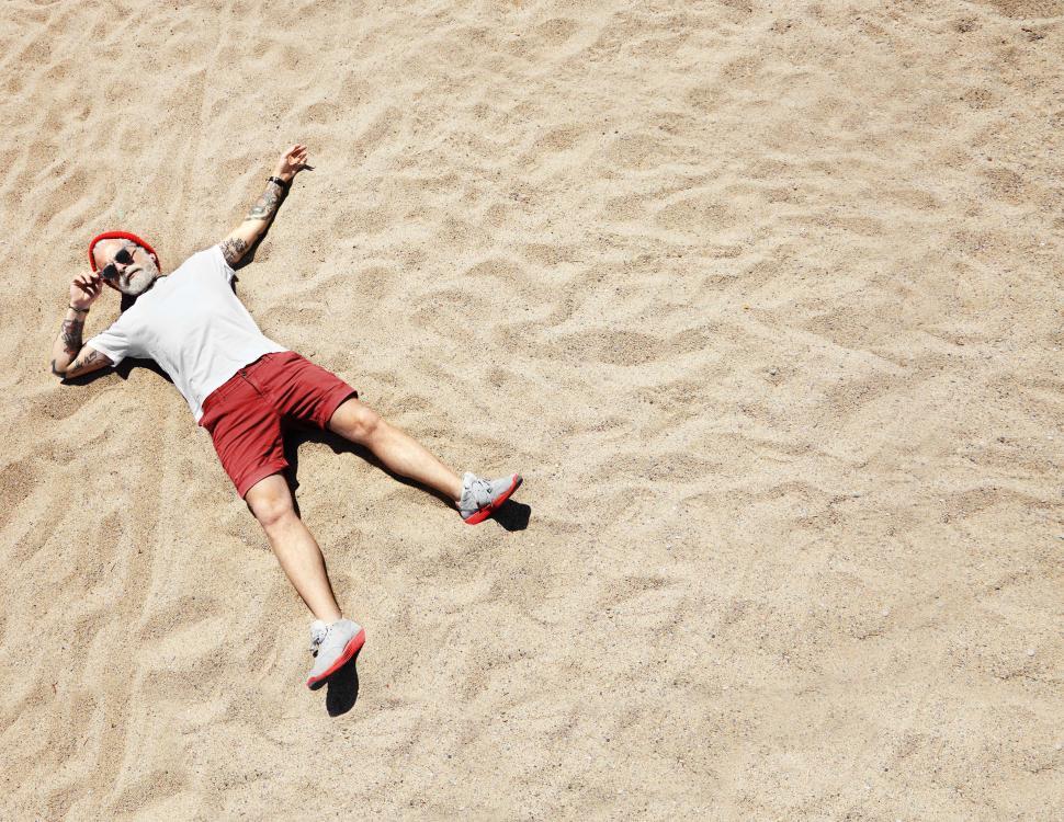 Free Image of Man lies on the sandy beach alone 