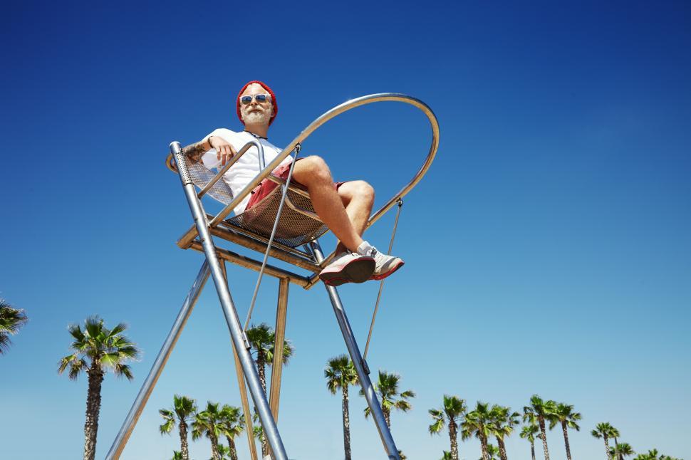 Free Image of Bearded man sitting in lifeguard chair at the beach 