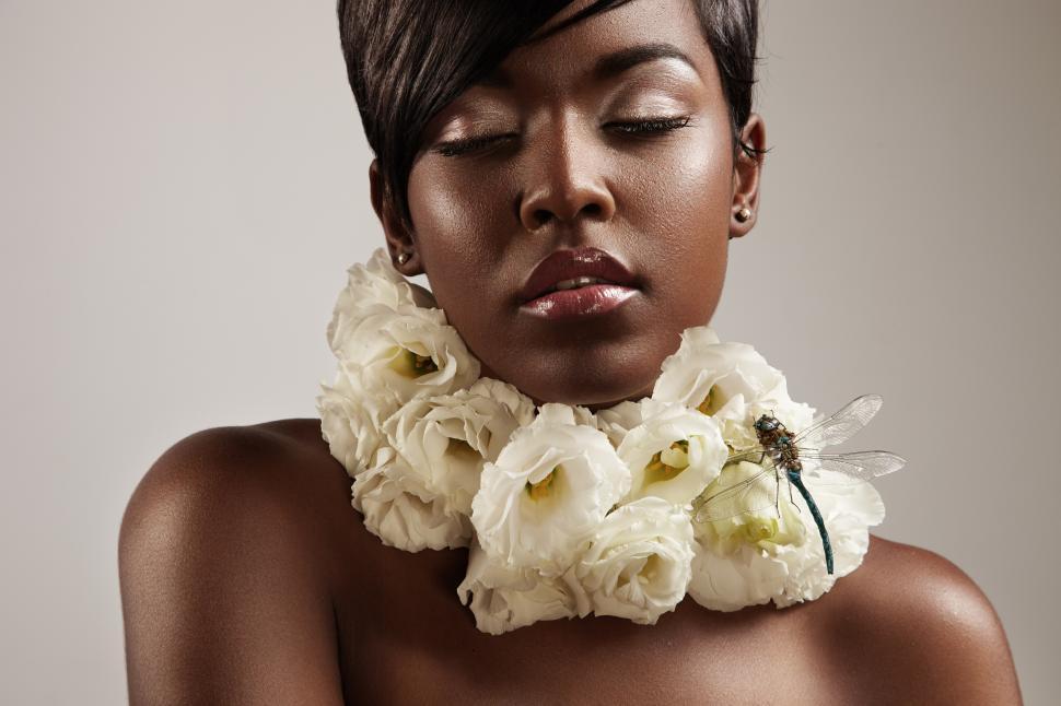Free Image of Black woman with eyes closed and flowers around her neck 