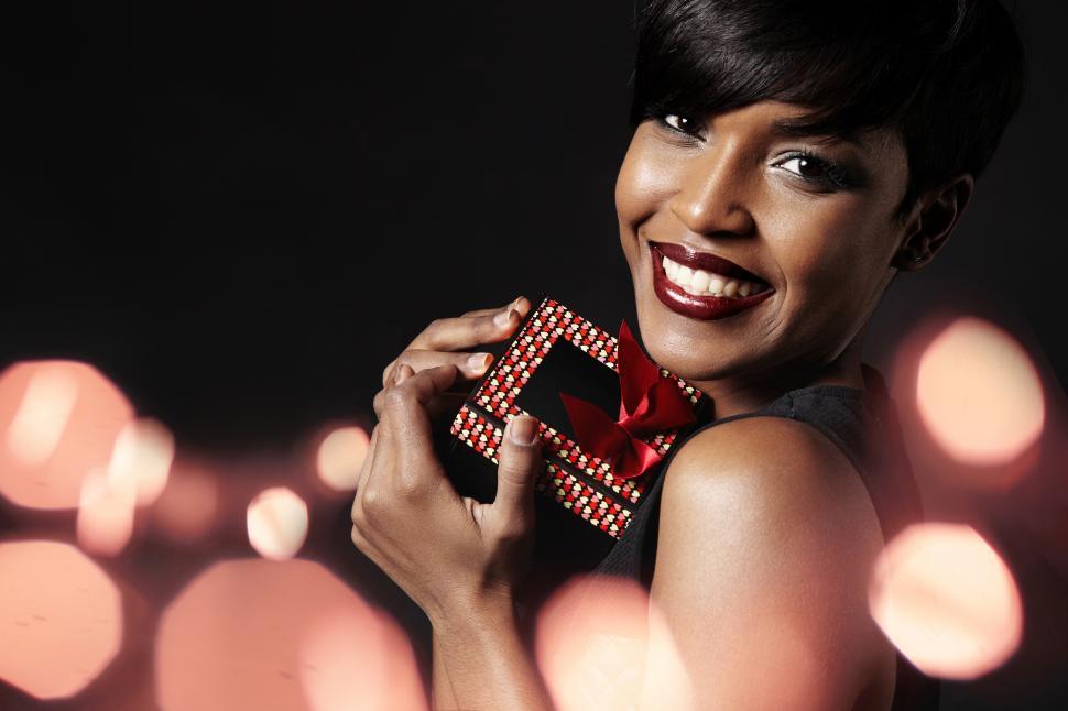 Free Image of beauty woman clutches an elegant gift, red bokeh in the background 