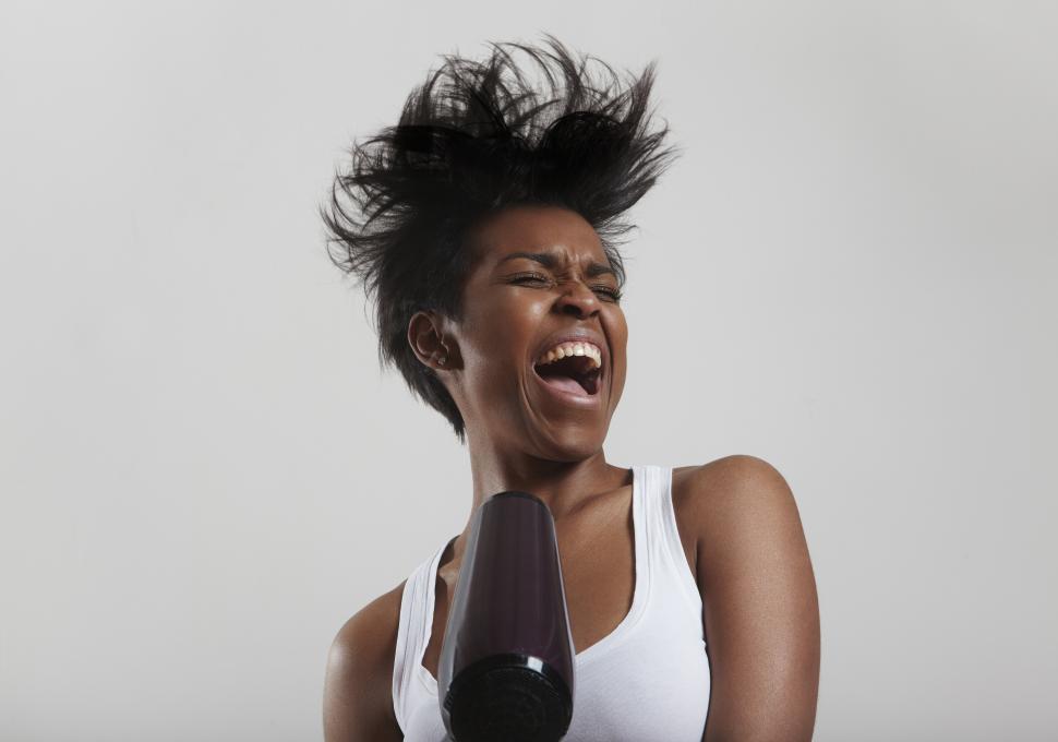 Free Image of black woman having a good time drying her hair and singing 