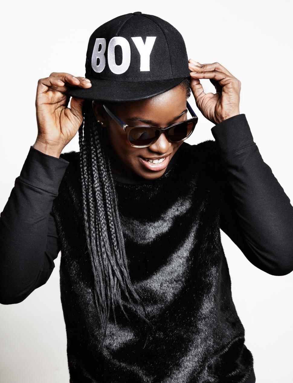 Free Image of Stylish black woman in sunglasses touching a cap 
