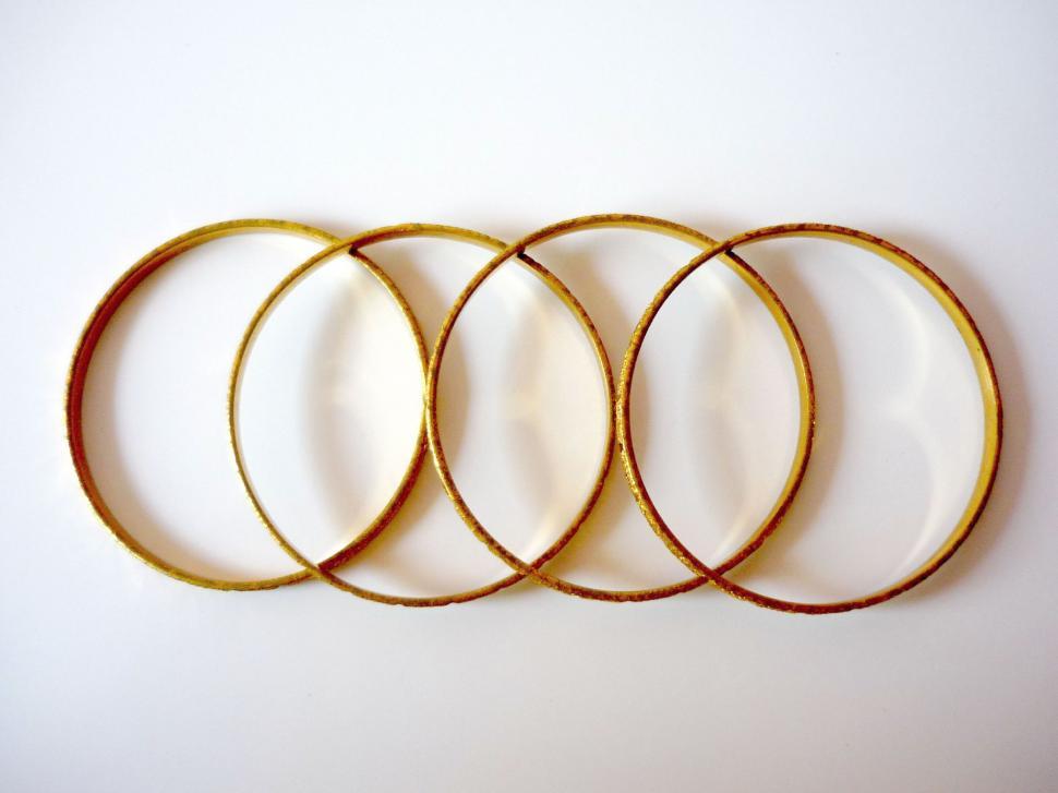 Free Image of Four Gold Colored Rings on White Surface 