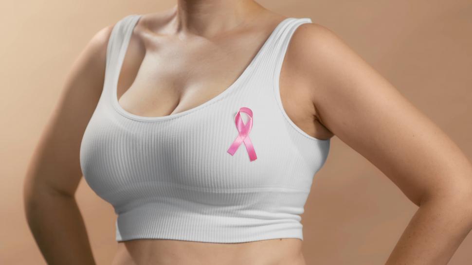 Free Image of closeup of female body with pink ribbon pinned to sports bra 