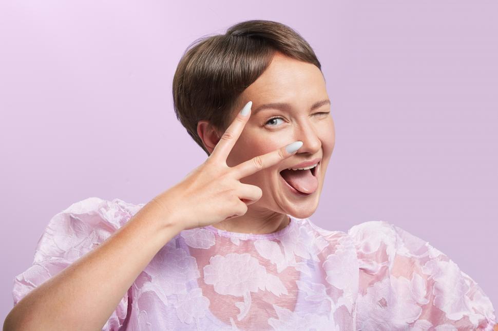 Free Image of happy woman winking through two fingers 