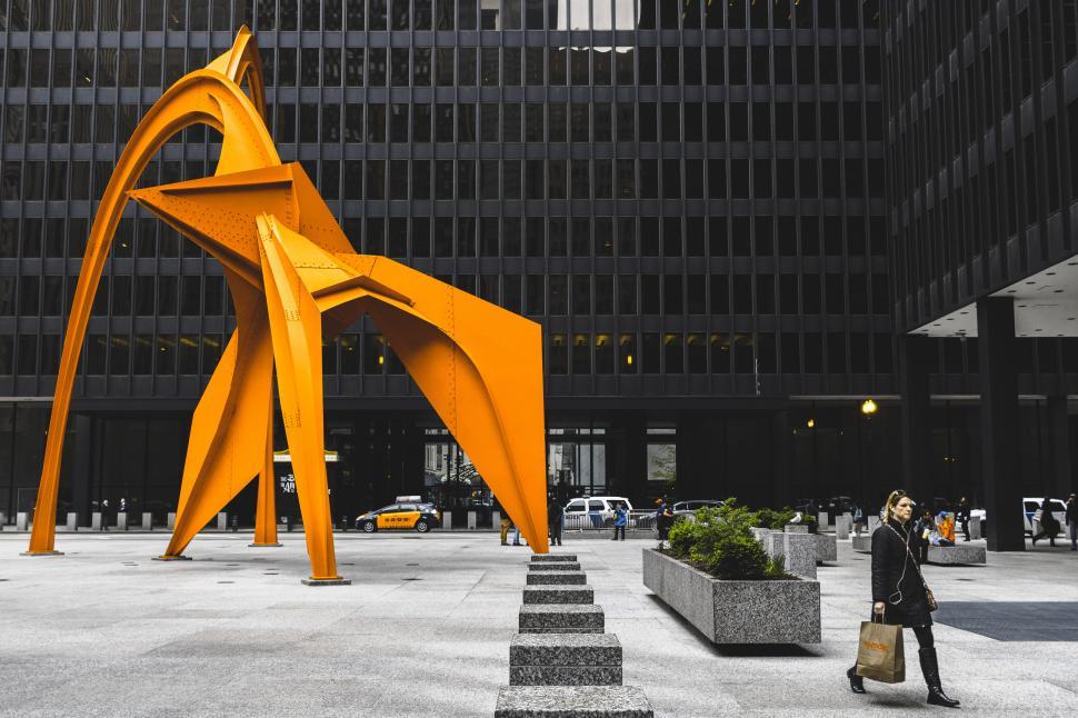 Free Image of Photo of a woman posing in front of a vibrant orange sculpture 