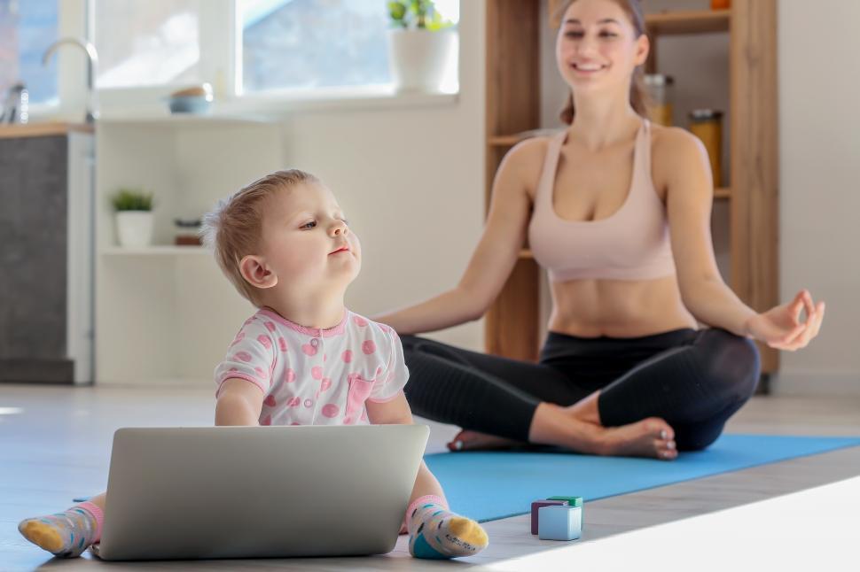Free Image of A woman and a baby sitting on a yoga mat 