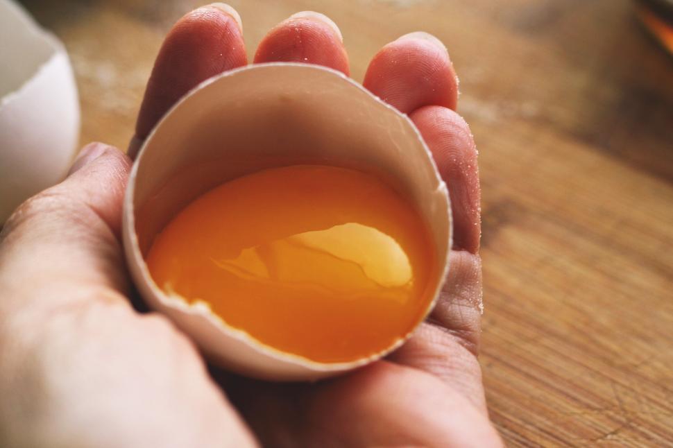 Free Image of A hand holding an egg shell with yolk in it 