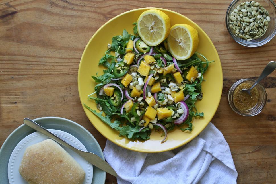 Free Image of A plate of salad with lemons and a bread on a wooden table 