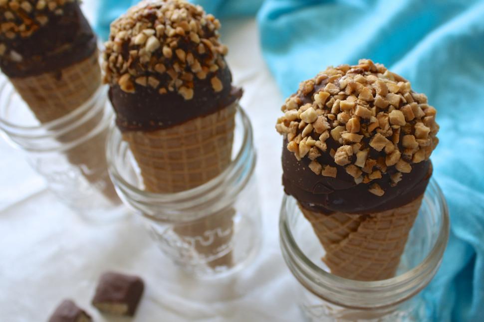 Free Image of Ice cream cones with chocolate toppings and nuts in them 