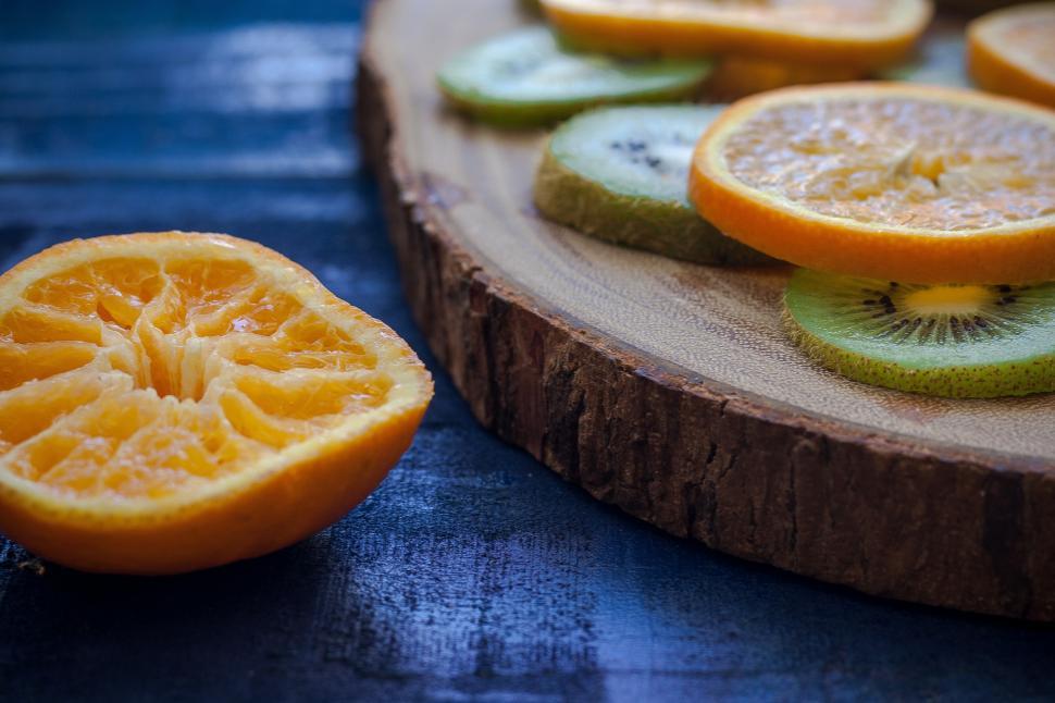 Free Image of A sliced orange and kiwi on a wood plate 