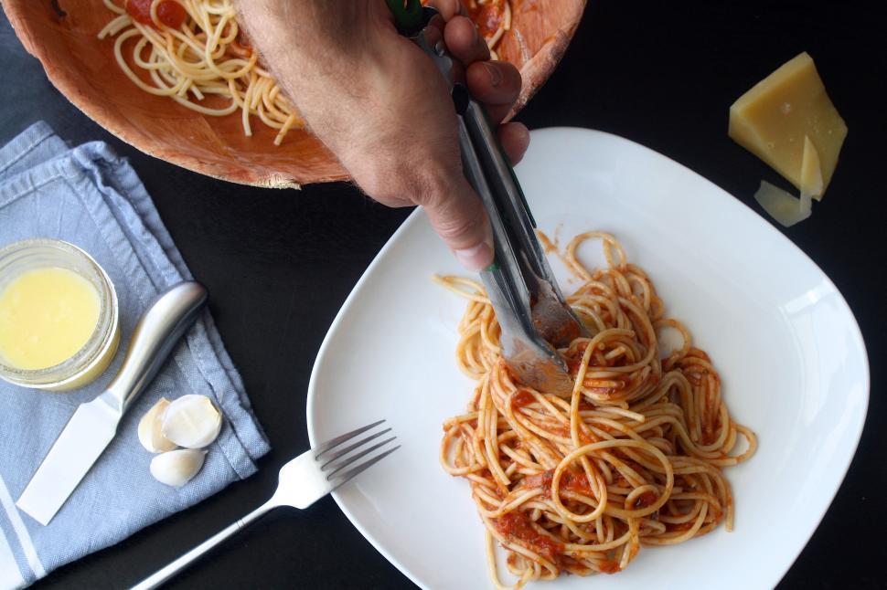 Free Image of A person holding tongs to a plate of spaghetti 