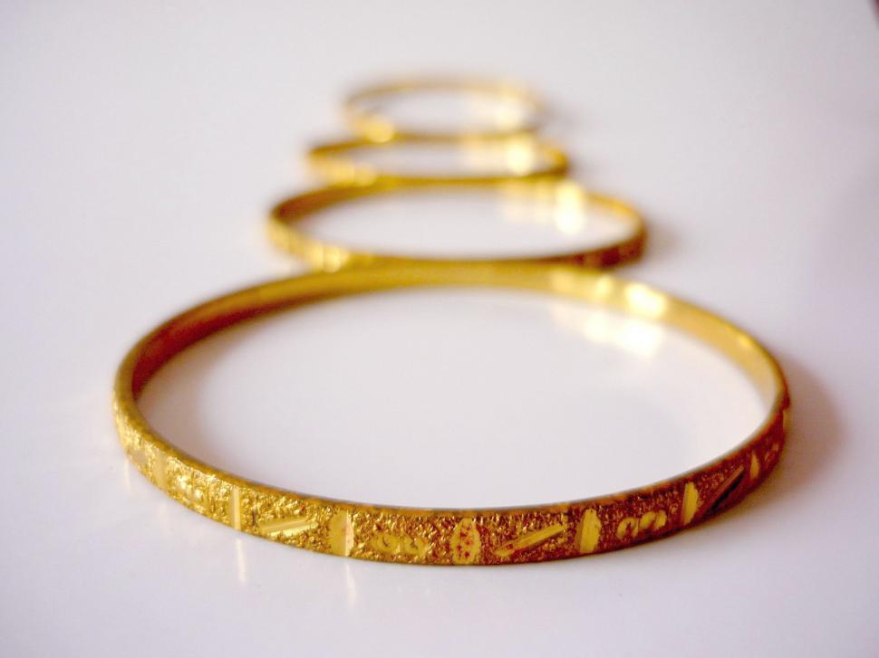 Free Image of Three Gold Bracelets on Table 