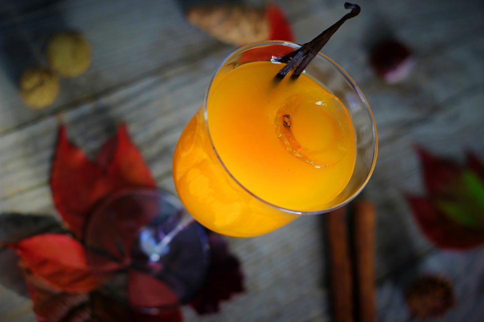 Free Image of A glass of orange liquid with a vanilla stick 