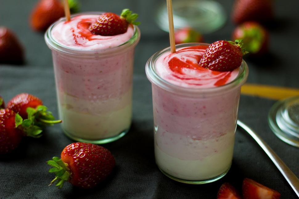 Free Image of Two glasses of yogurt with strawberries on top 