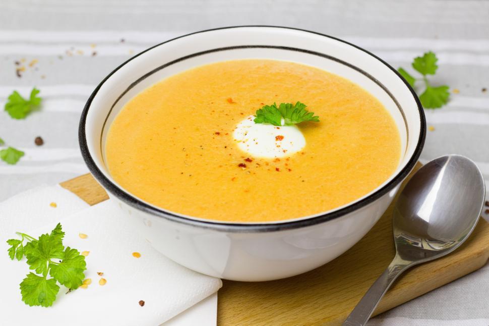 Free Image of A bowl of soup with a spoon and a fork 