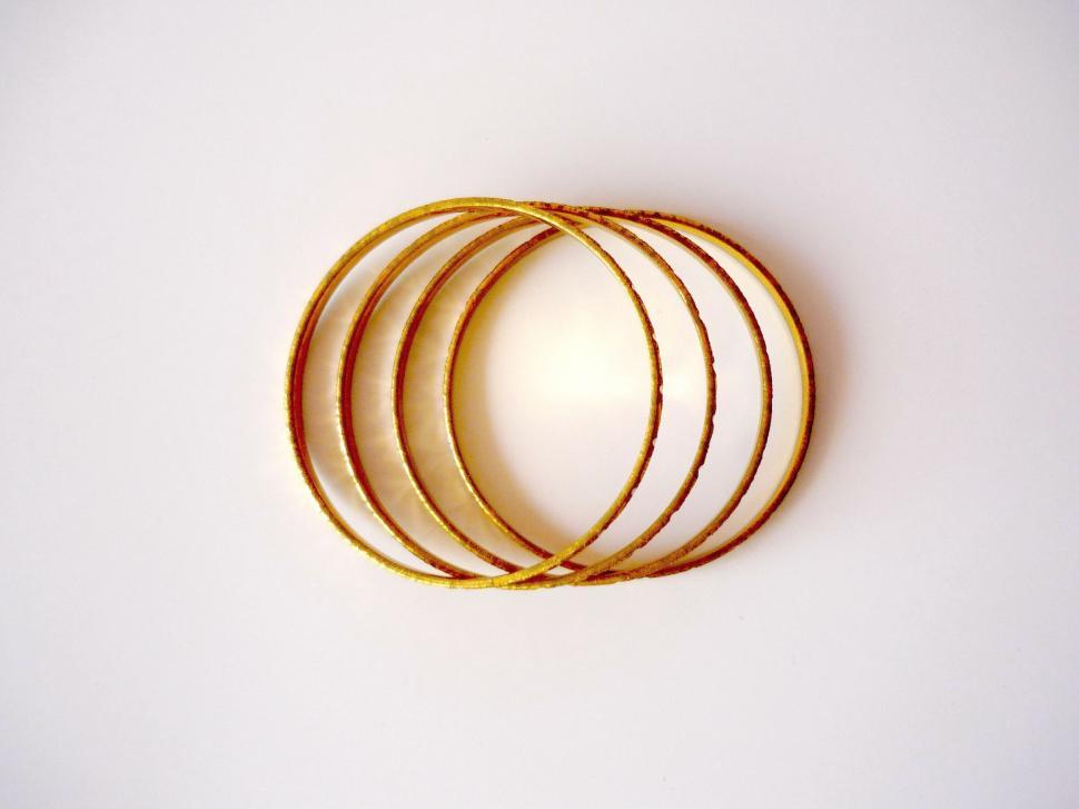 Free Image of Set of Four Gold Bangles on White Background 