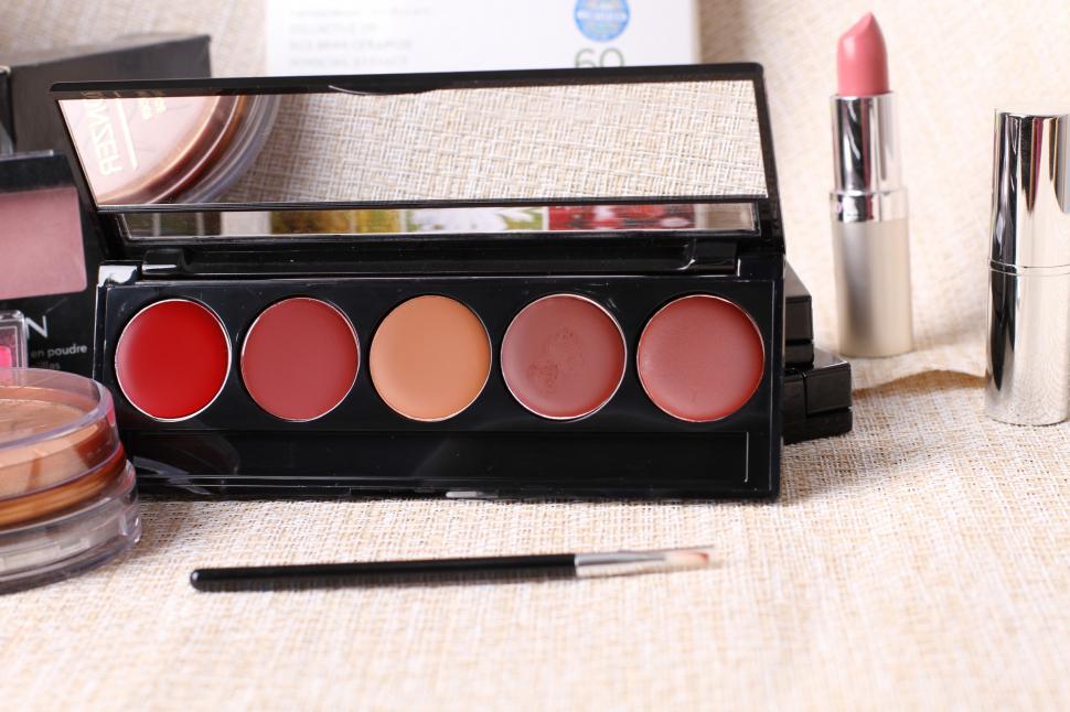 Free Image of A makeup palette with different colors of lipstick and a brush 