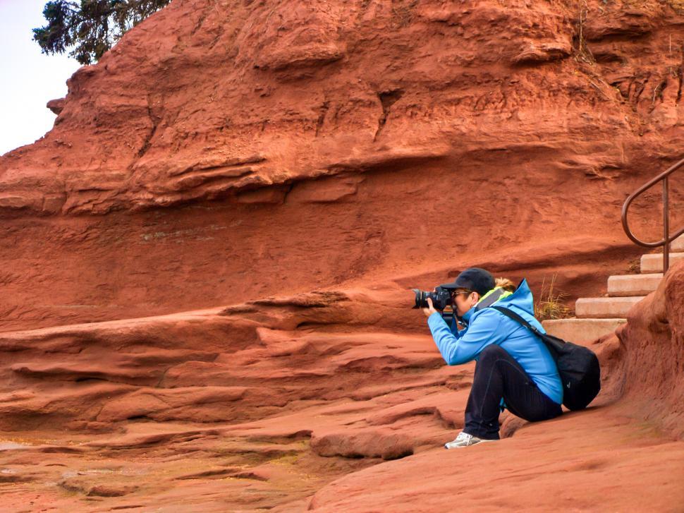 Free Image of A woman taking a picture of a red rock 