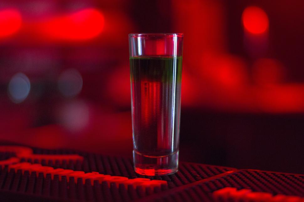 Free Image of A shot glass with a green liquid on a black surface 