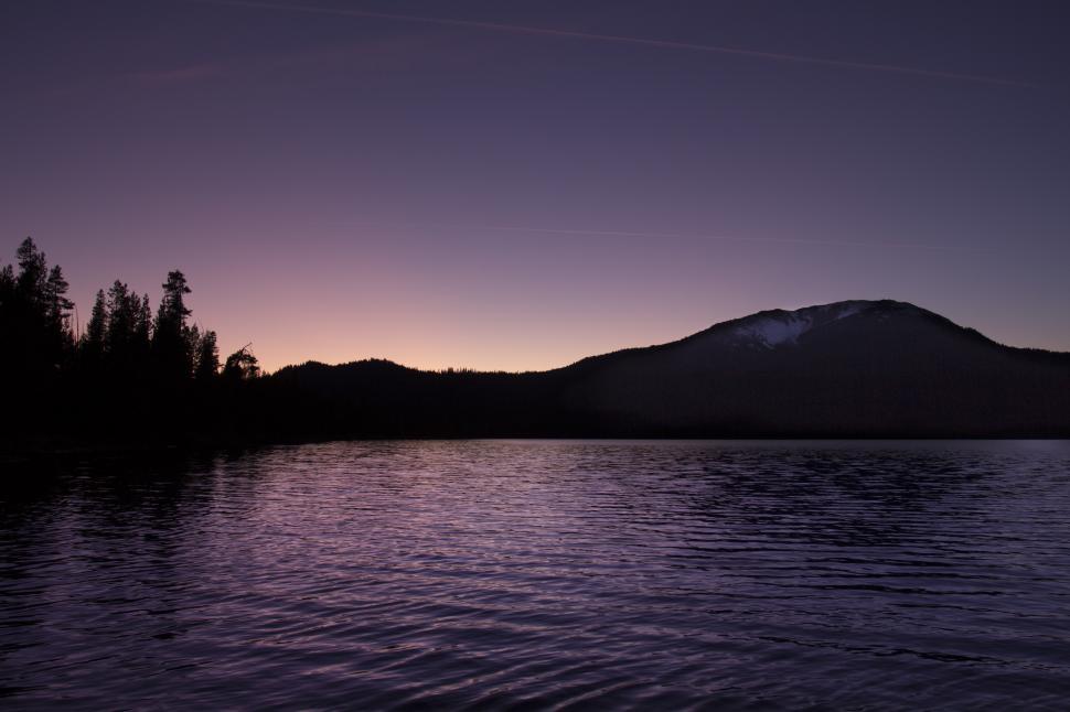 Free Image of A lake with trees and mountains in the background 