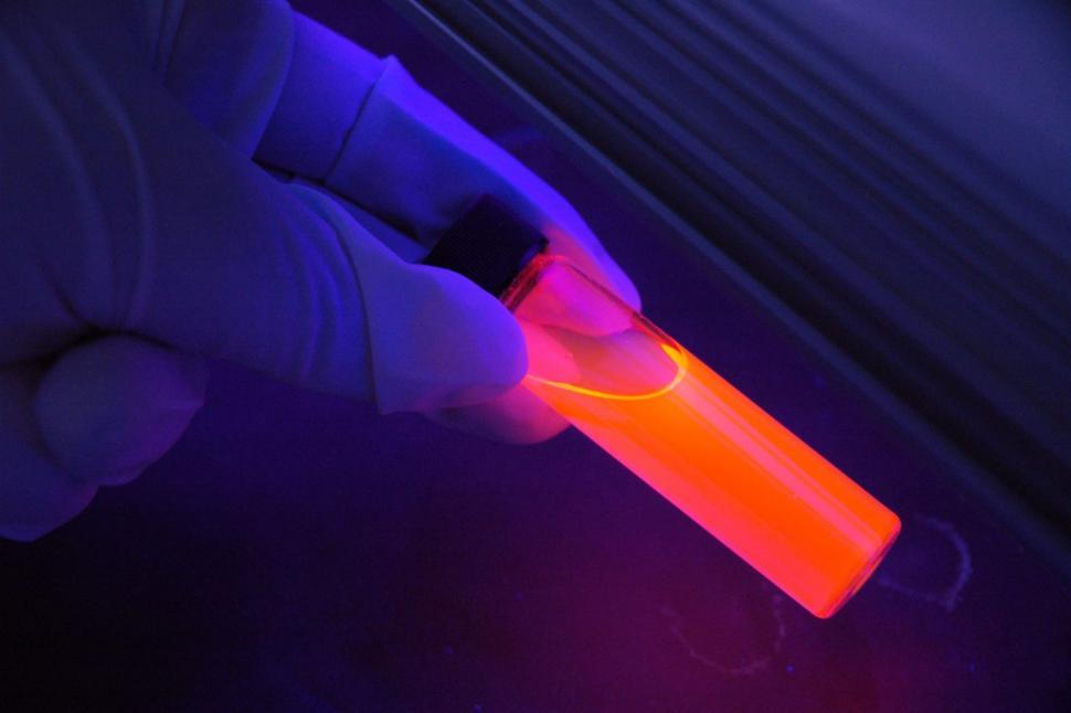 Free Image of A hand holding a tube with orange liquid 