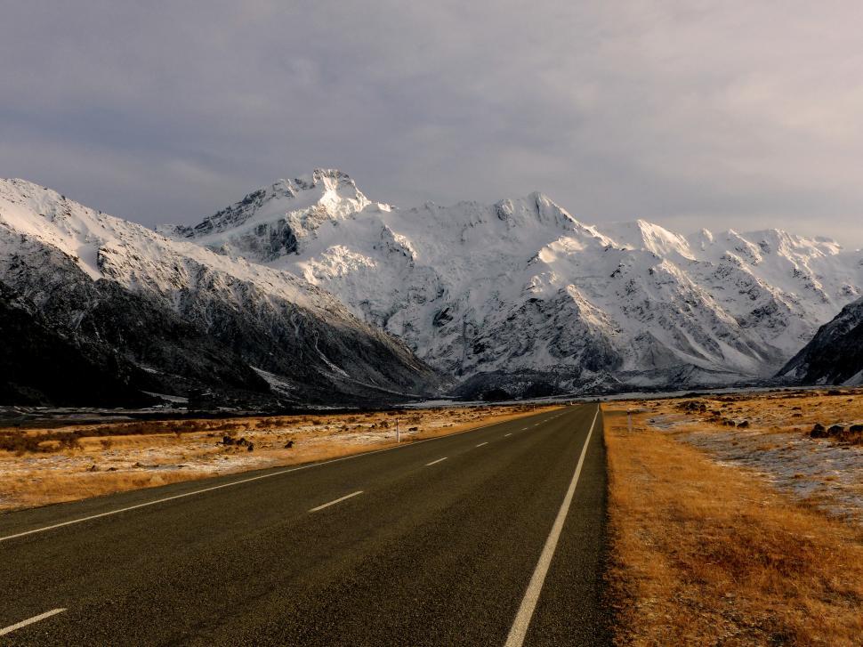 Free Image of A road with snow covered mountains in the background 