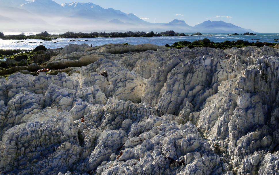 Free Image of A rocky beach with mountains in the background 