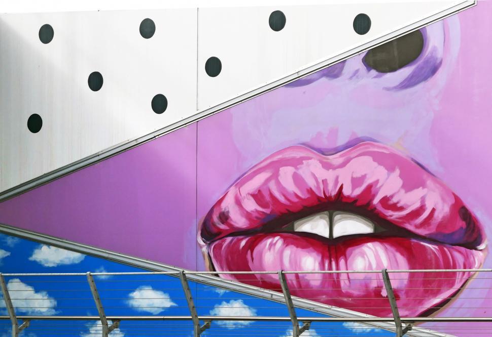 Free Image of A mural of lips and mouth with blue sky and clouds 