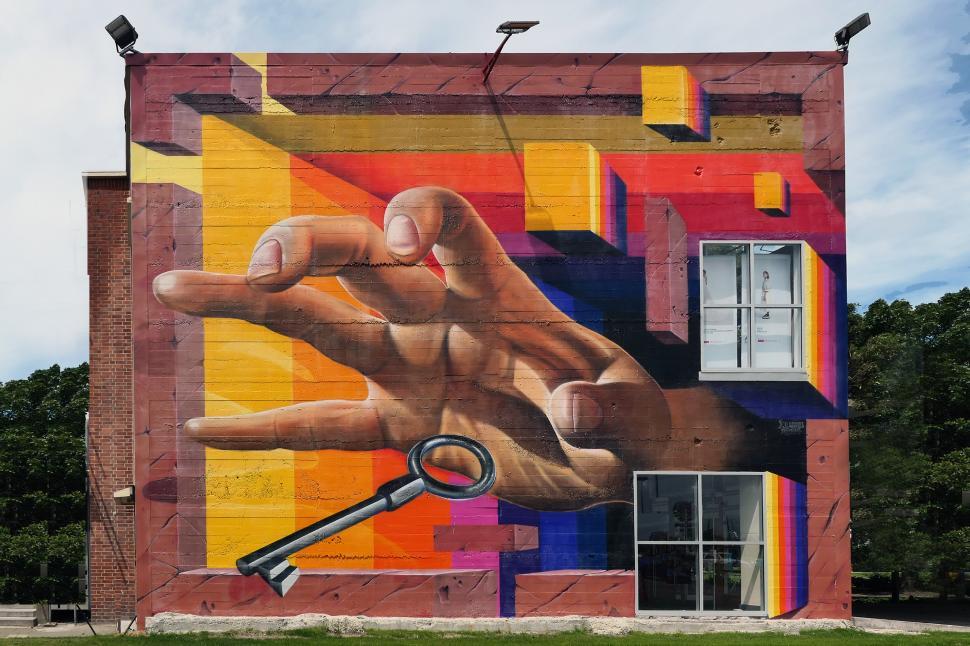 Free Image of A mural of a hand and a key on a brick wall 
