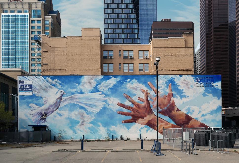 Free Image of A mural of hands and doves in a parking lot 