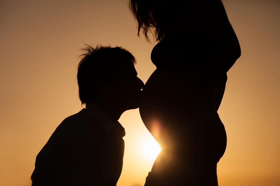Free Image of A silhouette of a man kissing a pregnant woman s belly 