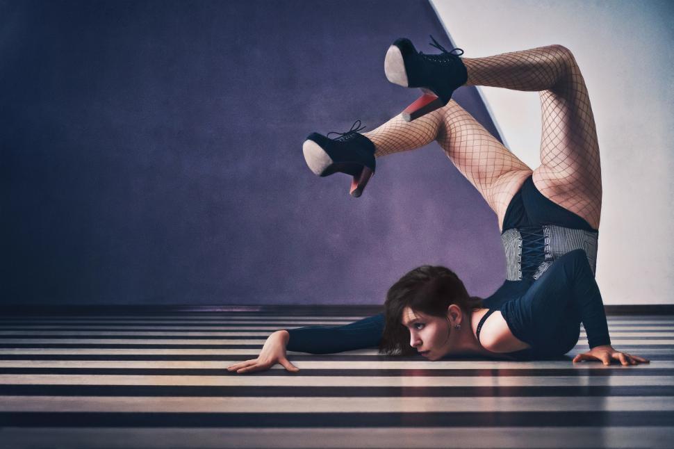 Free Image of A contorted woman lying on a striped floor 