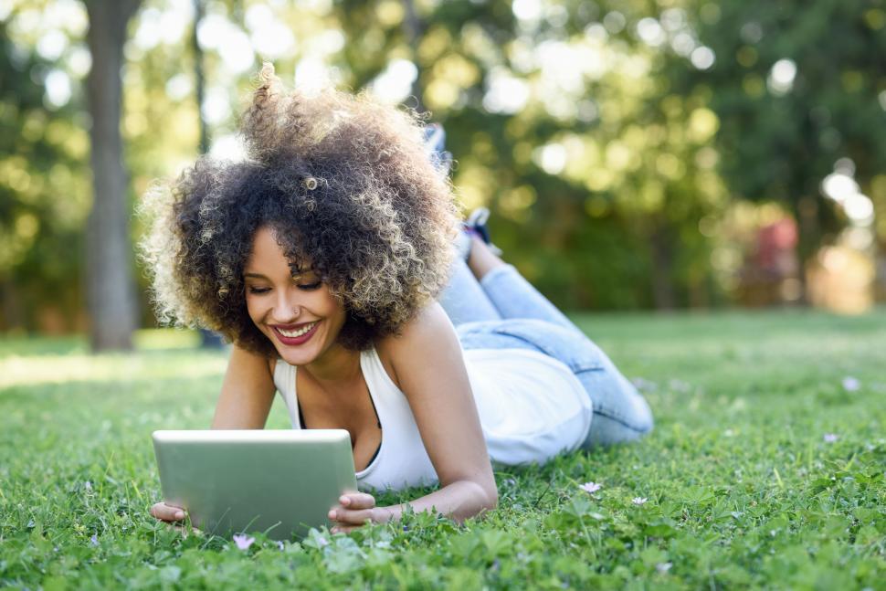 Free Image of Mixed woman with afro hairstyle looking at her tablet computer 