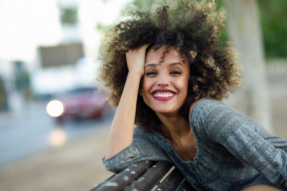 Free Image of Young black woman with afro hairstyle smiling in urban background 