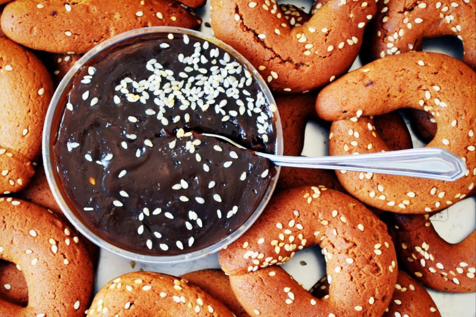 Free Image of A bowl of chocolate spread with sesame seeds on top of a pile of cookies 