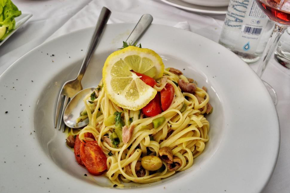Free Image of A plate of pasta with a lemon slice and a fork 