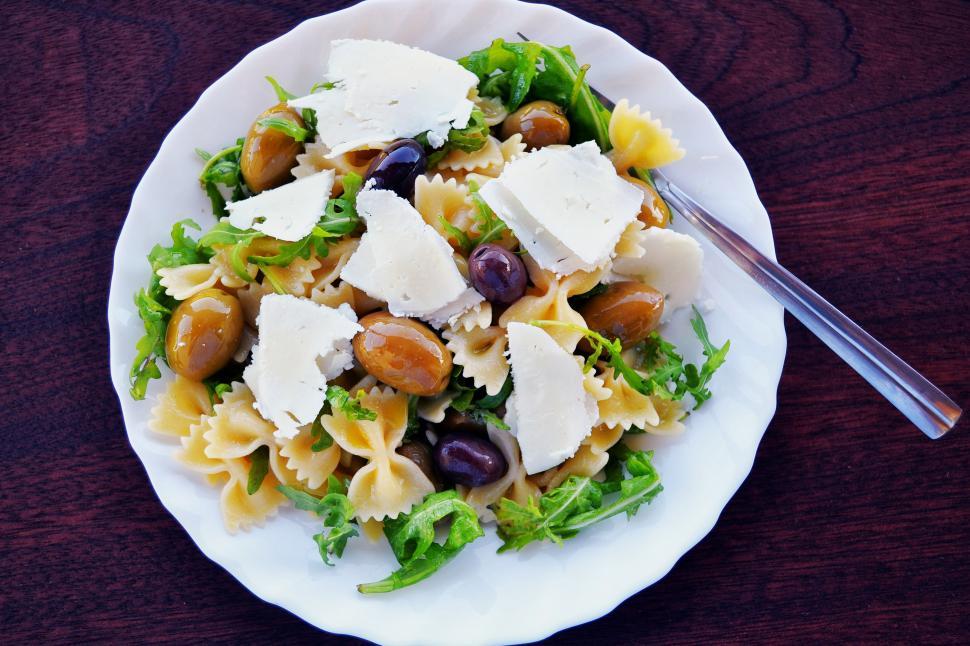 Free Image of A plate of pasta salad with cheese and olives 
