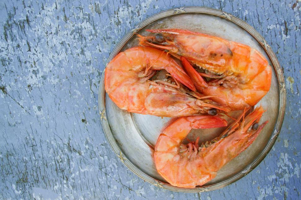 Free Image of A plate of shrimp on a blue surface 