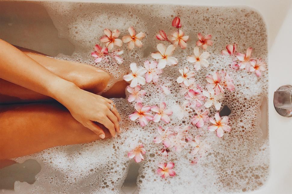 Free Image of A person s legs in a bathtub with flowers 